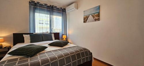 a bedroom with a bed with two pillows and a window at Modern 3 Bed Flat - Beaches, Expo & City Fun - Your Gateway to Lisbon in Montijo