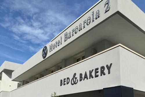a white building with a sign for bed and bakery at Hotel Barcarola 2 in Marina di Campo