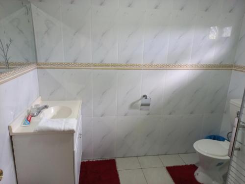a white bathroom with a toilet and a sink at Le Seraphine's Accommodation in Apia