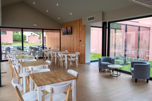 a restaurant with tables and chairs and windows at Canto`s Green Garden, Apartamentos Turísticos & SPA, 4 Estrelas in Furnas