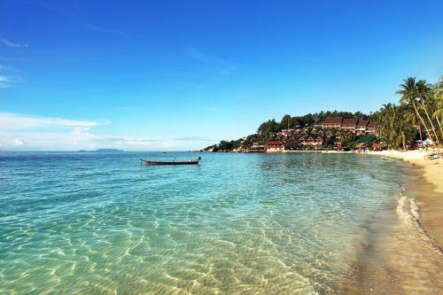 a boat in the water next to a beach at Crocus Garden in Haad Yao