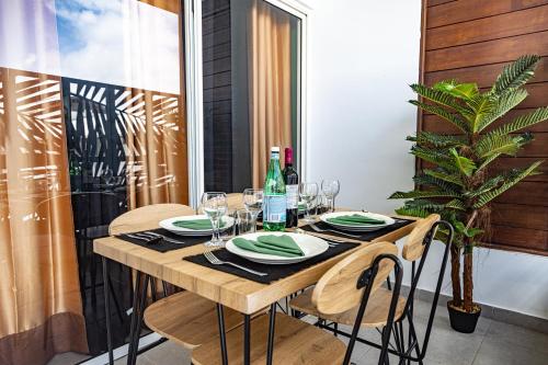 a wooden table with plates and wine glasses on a balcony at Le Loft industriel à la Zac Hibiscus - Terrasse in Trou Biron