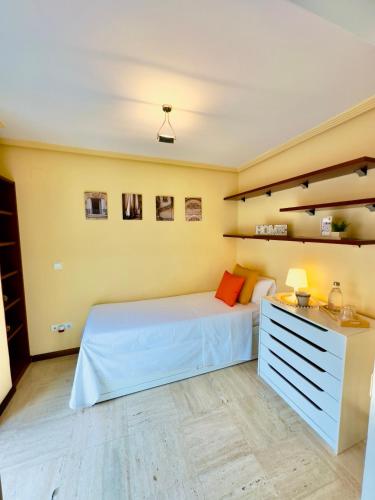 sypialnia z białym łóżkiem, komodą i półkami w obiekcie Habitación en el corazón de Alicante con vista Jardín w Alicante