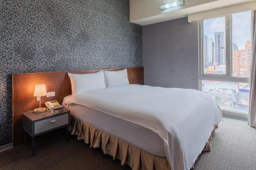 a hotel room with a large bed and a window at The Galerie Hotel in Taichung