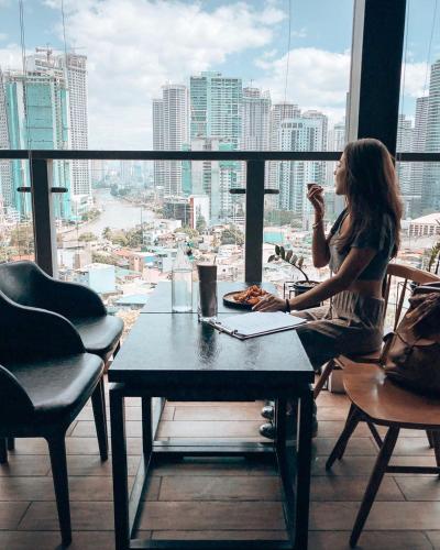 a woman sitting at a table in front of a window at Lub d Manila Makati - Central Makati, Near Nightlife in Manila