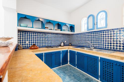a blue kitchen with blue cabinets and blue tiles at Riad Asilah 32 in Asilah
