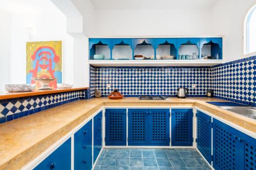 a kitchen with blue cabinets and blue tiles at Riad Asilah 32 in Asilah