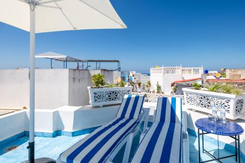 two blue chairs and an umbrella on a balcony at Riad Asilah 32 in Asilah