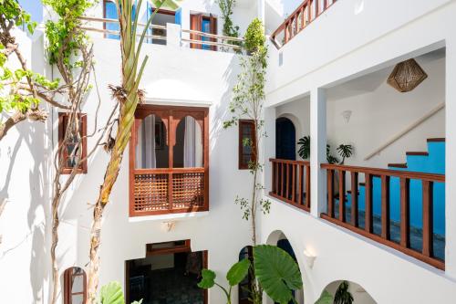 a house with white walls and a courtyard with trees at Riad Asilah 32 in Asilah