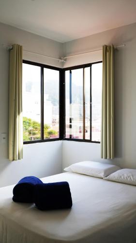 a bedroom with two beds and a large window at Residencial Dona Dina - Mestre Naro in Bombinhas