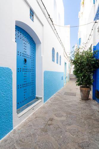a narrow alley with blue and white buildings at Riad Asilah 32 in Asilah