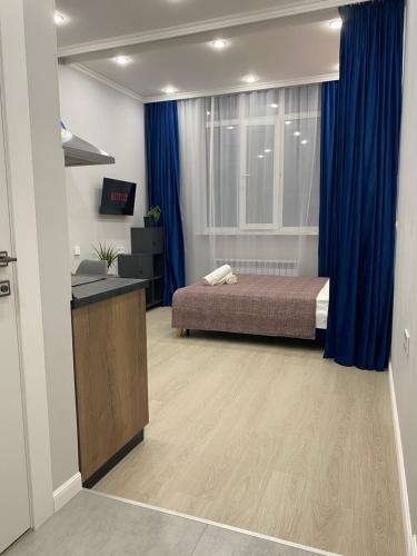 a bedroom with a bed and a blue curtain at Contento Apartments in Almaty