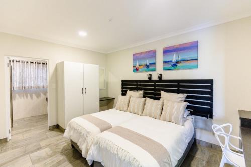 a bedroom with a large white bed and two paintings at 8 On Eagle Bed & Breakfast Room 4 in Port Shepstone