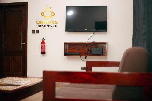 ein Wohnzimmer mit einem Fernseher an der Wand in der Unterkunft ORADYS Residence in Sanguéra
