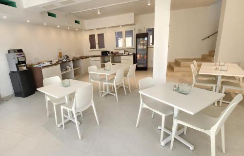 a restaurant with white tables and chairs and a kitchen at Hotel Borgo Dell'Orso in Palau