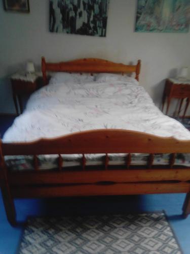 a bed with a wooden frame in a bedroom at Happy days in Spézet