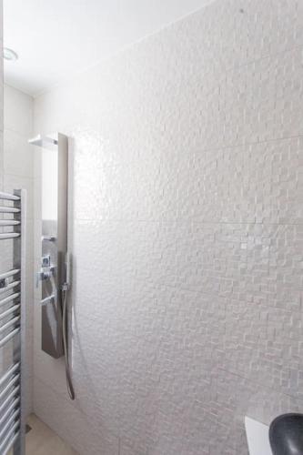La salle de bains est pourvue d'une douche dans un mur blanc. dans l'établissement Luxury & quiet Paris 16 Auteuil, à Paris