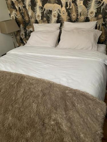 un lit avec des draps blancs et des oreillers dans une chambre dans l'établissement Luxury & quiet Paris 16 Auteuil, à Paris