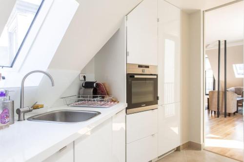 une cuisine blanche avec un évier et une cuisinière dans l'établissement Luxury & quiet Paris 16 Auteuil, à Paris