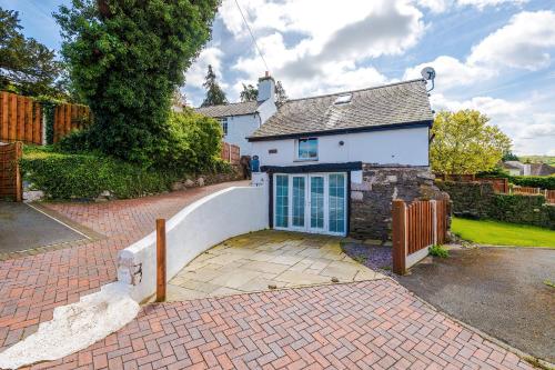 a white house with a gate and a brick driveway at 'Apple Store' - Mochdre Cottages in Mochdre