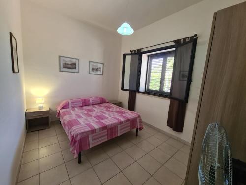 a bedroom with a pink bed and a window at Casa il Sole Casevacanze Ferienwohnung Daniele Furco in Castellammare del Golfo