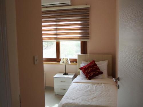 1 dormitorio con cama y ventana con sombra en Holiday apartment with astonishing views in Esentepe, en Ayios Yeoryios