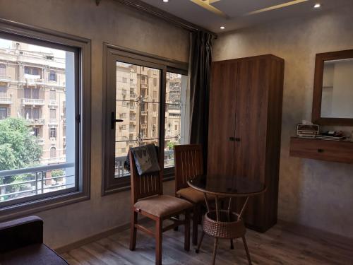 カイロにあるswiss hotel downtownのテーブルと椅子2脚、窓が備わる客室です。