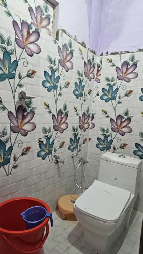 ein Bad mit einem WC und Blumen an der Wand in der Unterkunft Rana Homestay in Ukhimath