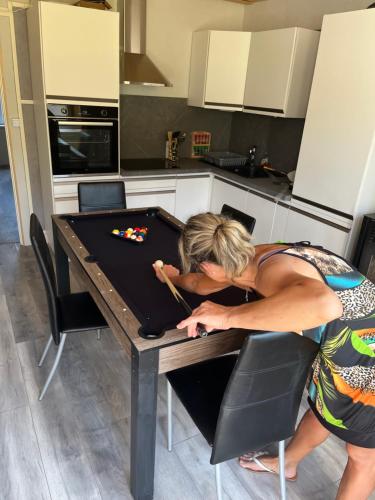 Une femme se penchant sur une table dans une cuisine dans l'établissement gite du Breuchin, à La Longine