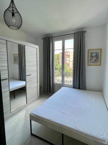 une chambre blanche avec un lit et un miroir dans l'établissement Spacieux appartement à Nice, à Nice