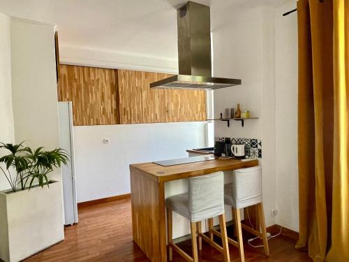 - une cuisine avec une table en bois et des chaises blanches dans l'établissement Spacieux appartement à Nice, à Nice