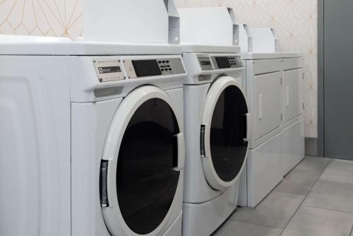 two white washing machines in a laundry room at Home2 Suites by Hilton Buffalo Airport/ Galleria Mall in Cheektowaga