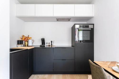 a kitchen with white cabinets and a black refrigerator at Sunny haven in Antwerp
