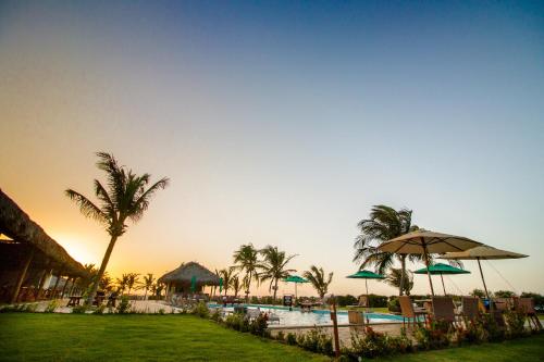 a pool with umbrellas and palm trees and a resort at Manati in Barra Grande