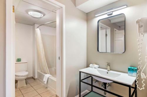 a bathroom with a sink and a toilet and a mirror at Black Bear Inn, an Ascend Collection Hotel in Orono