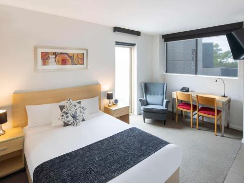 城堡山Mantra Castle Hill Sydney, an Accor Hotel的一间卧室，配有一张床、一张桌子和一把椅子