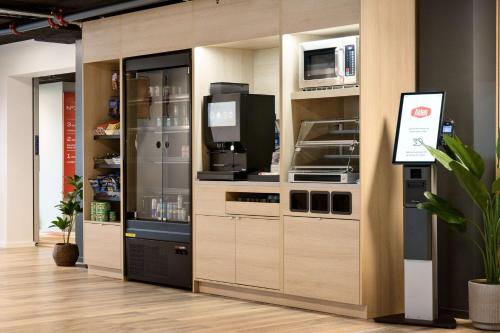 a kitchen with wooden cabinets with a microwave and a tv at Aiden by Best Western Lolland in Holeby