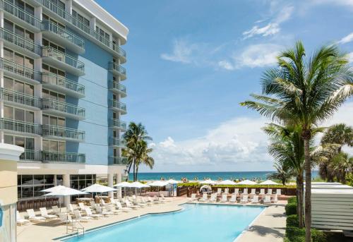 an image of the pool at the resort with chairs and umbrellas at The Singer Oceanfront Resort, Curio Collection by Hilton in Palm Beach Shores