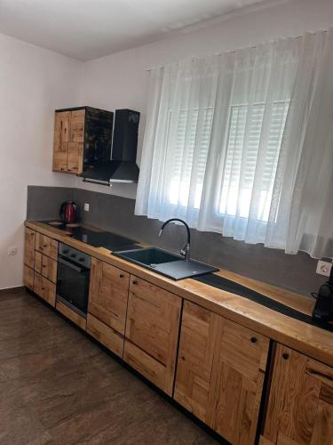 a kitchen with wooden cabinets and a sink and windows at Villa Ellania Milos in Adamantas