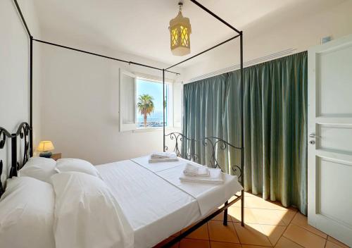 a bedroom with a large white bed and a window at Solemar Sicilia - Casa Aura in Porticello