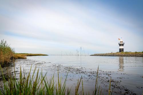 a lighthouse in the middle of a body of water at Die Ferienwohnung direkt am Meer in Wremen