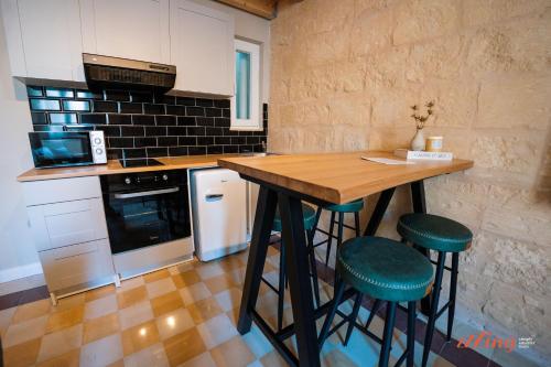 une cuisine avec une table en bois et deux tabourets verts dans l'établissement The Florian Boutique Guesthouse by Zzzing, à Cospicua
