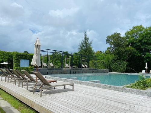 a swimming pool with lounge chairs and an umbrella at The Gallery Hotel Nai Harn in Nai Harn Beach