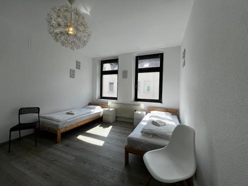 a room with two beds and a chair and a chandelier at Vollausgestatte Wohnung mit, WLAN, TV in jedem Schlafzimmer, Einzelbetten, Bad, Garten in Crimmitschau