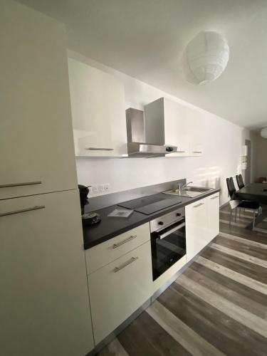 une cuisine avec des armoires blanches et un four à plaques de cuisson dans l'établissement Alsace séjours, à Pulversheim