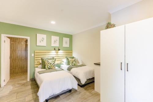two beds in a bedroom with green walls at 8 On Eagle Bed & Breakfast Room 3 in Umtentweni