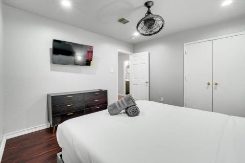 a white bedroom with a bed and a flat screen tv at Sophisticated 5BR 2,5BA Holiday Villa - Pool Sauna Hot Tub in Grand Prairie