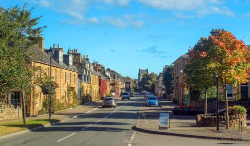 a city street with houses and cars on the road at Ash Mill - Dornoch in Dornoch