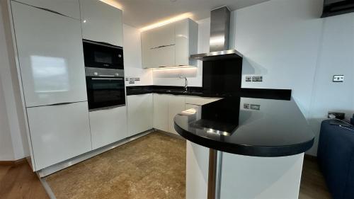 a kitchen with white cabinets and a black counter top at Ocean Spa Plaza Luxury Suite in Gibraltar