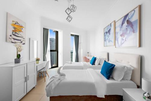 a white bedroom with two beds and a desk at Skyline Views 2BR Near Burj Khalifa & Dubai Mall with Pool Access in Dubai